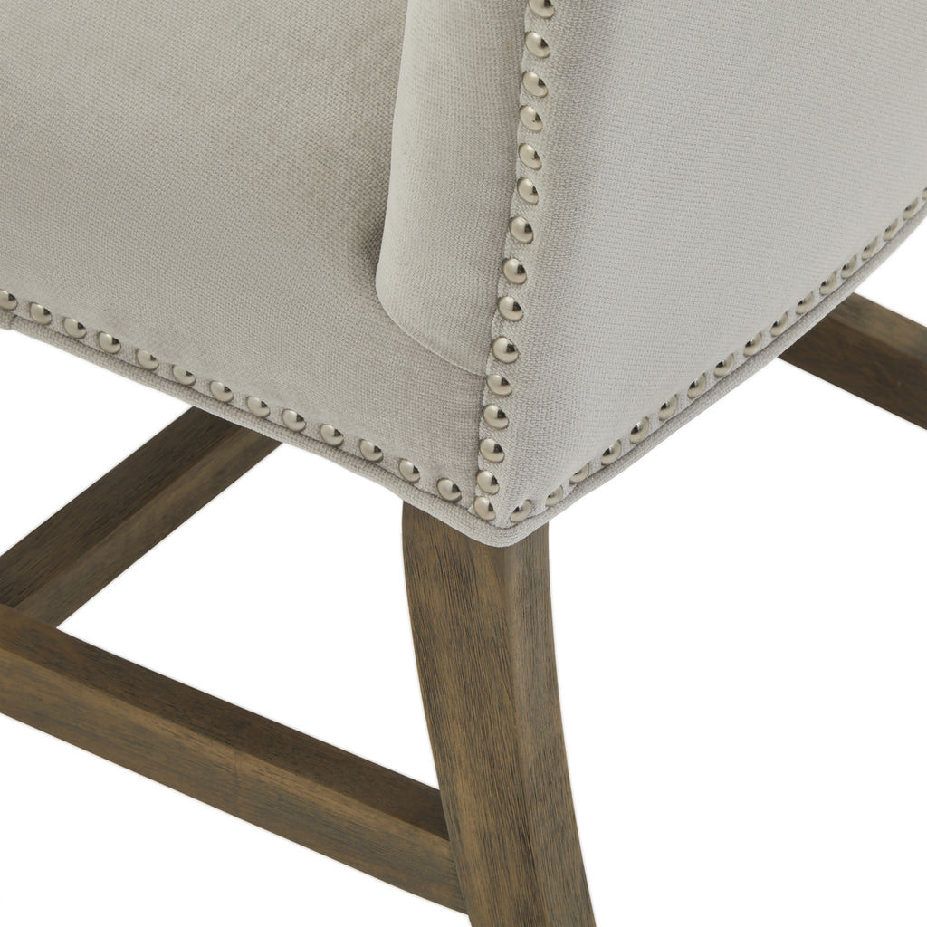 Close-up of the chair's lower back corner, showing the textured pale grey covering, reflective round studs and wood-grain appearance of the leg and stretchers.
