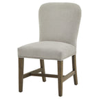 Front three-quarter view of the pale grey dining chair, showing its curved back, bright studs along the seat edge and brown legs with H-shaped stretchers.