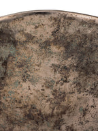 Close-up of the bowl's exterior beneath the rim, showing bronze tones with dark mottling and small green patches.