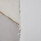 Detail of cream, off-white and grey painted sections meeting, showing fine surface texture and uneven overlapping edges.