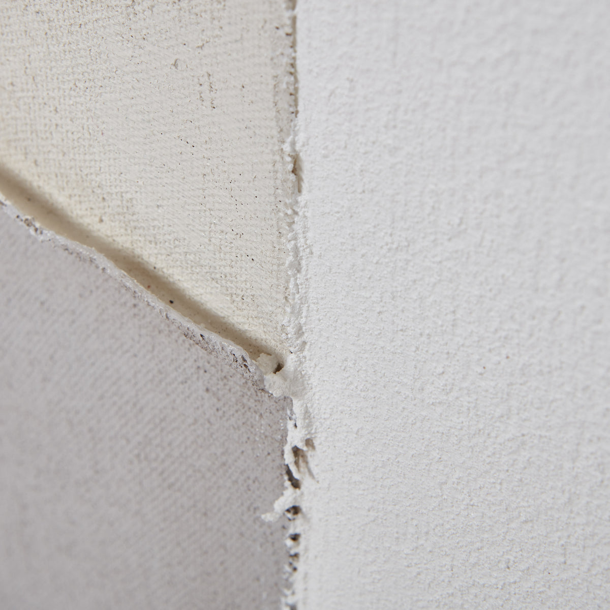 Detail of cream, off-white and grey painted sections meeting, showing fine surface texture and uneven overlapping edges.