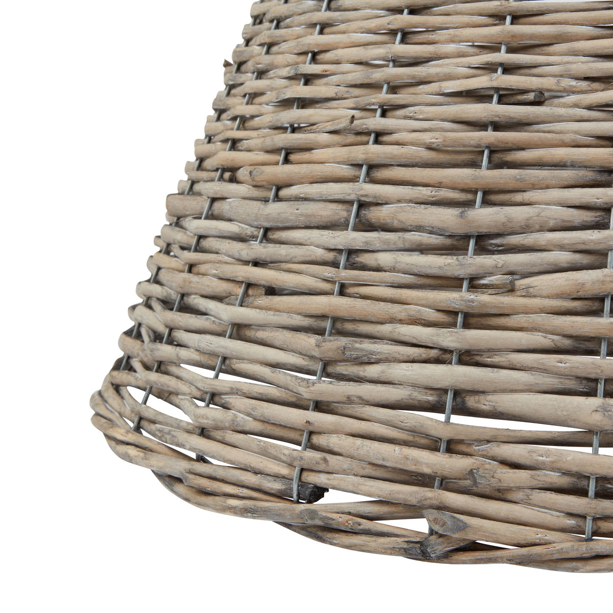 Detail of the tree collar's lower edge, showing uneven beige and grey-brown sticks, dark surface markings and gaps between the woven rows.