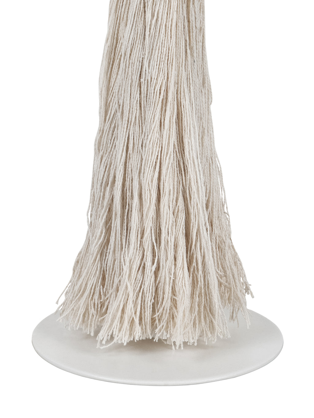 Close-up of loose cream tassel strands and their uneven ends above the lamp's smooth white circular foot.