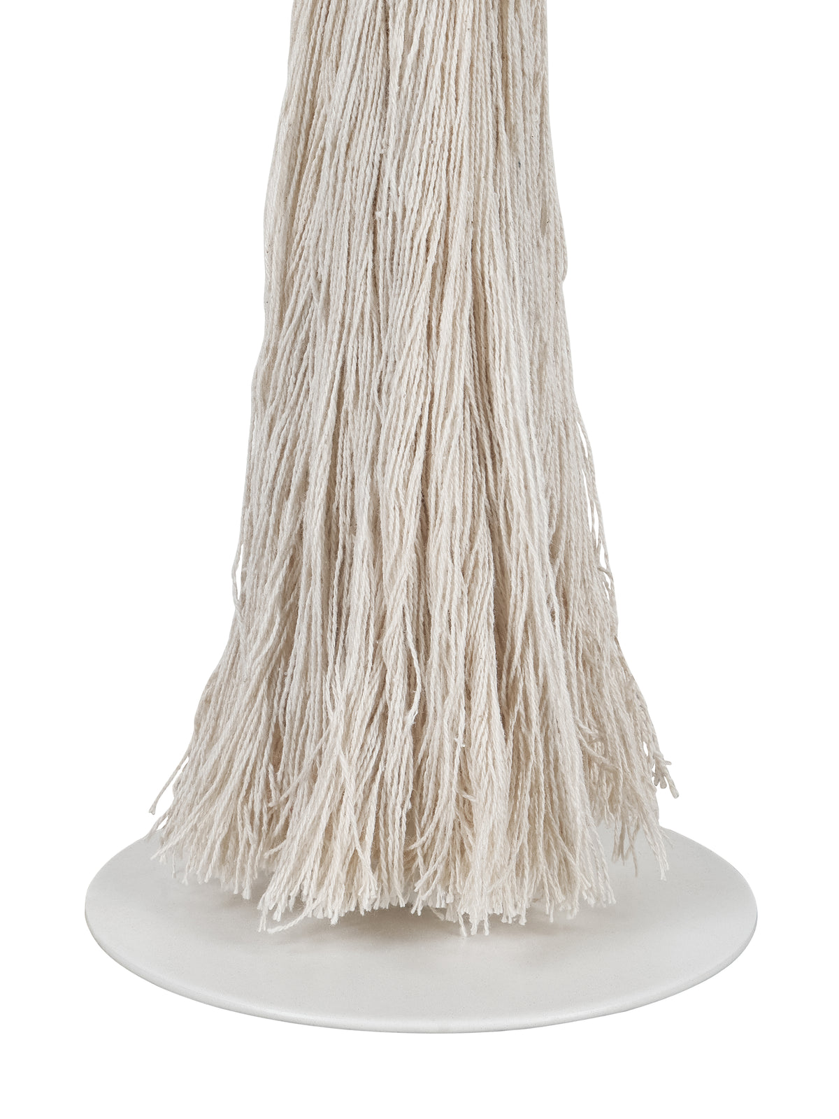Close-up of loose cream tassel strands and their uneven ends above the lamp's smooth white circular foot.