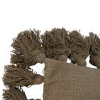 Close-up of a cushion corner, showing the textured weave and loose yarn tassels attached around the edges.