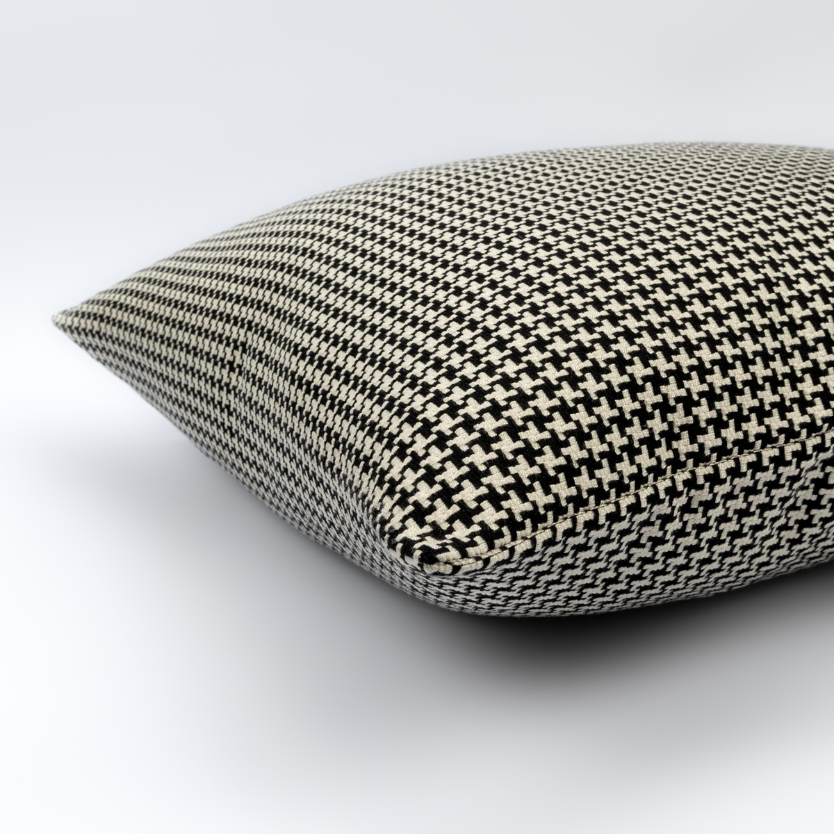 Angled view of the Tavira Cushion showing its black and cream houndstooth pattern
