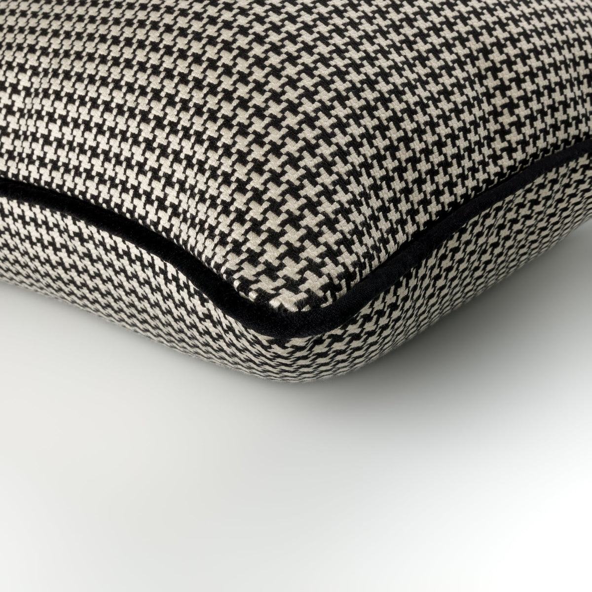 Close-up of the Tavira Cushion showing its black piping and houndstooth fabric