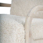 Close-up of the curved wooden arm and front leg beside the chair's textured cotton seat.