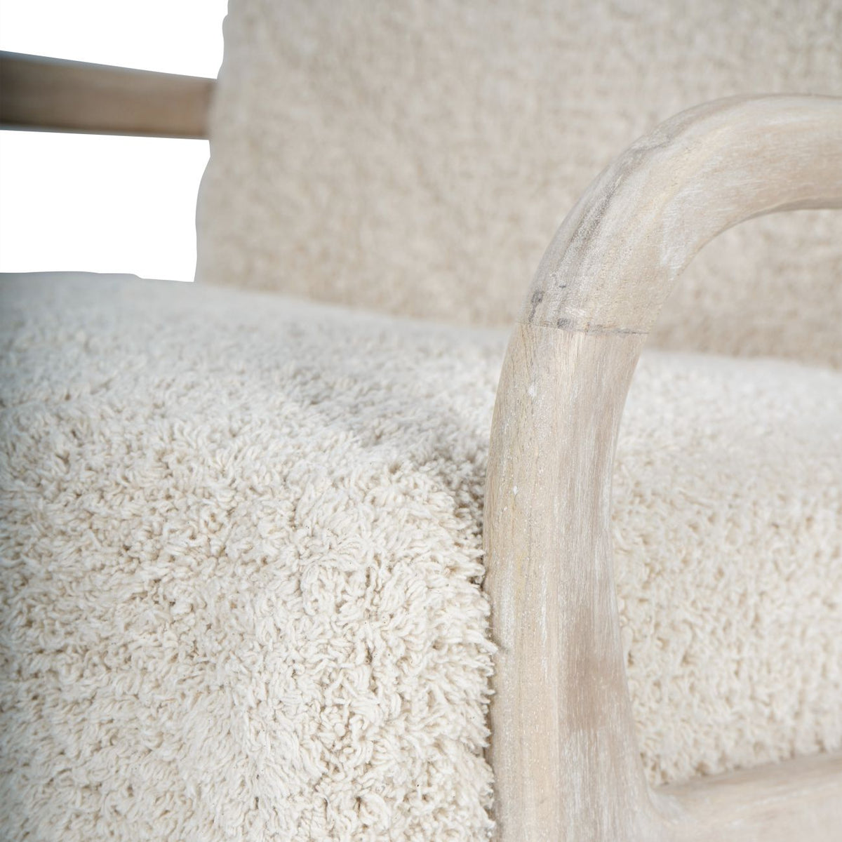 Close-up of the curved wooden arm and front leg beside the chair's textured cotton seat.
