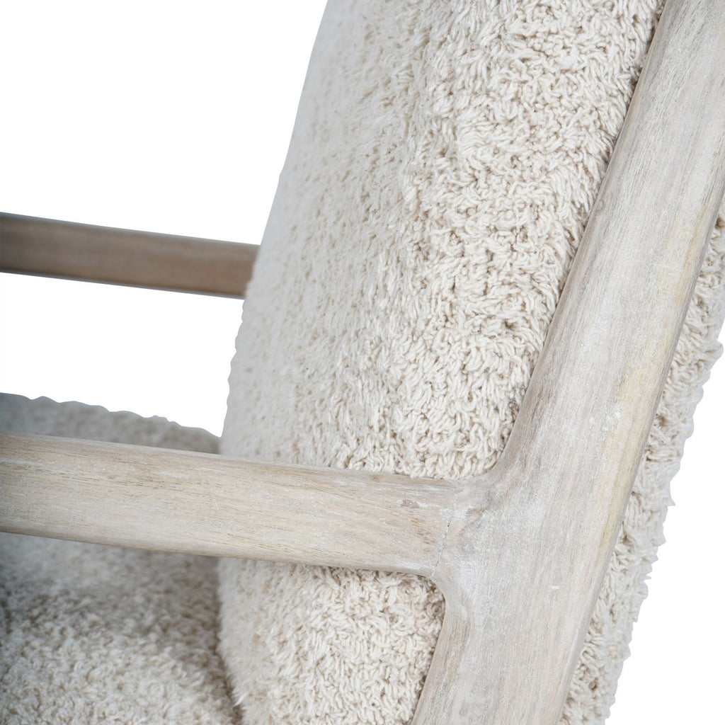 Detail of the whitewashed wooden arm meeting the back upright beside pale teddy upholstery.