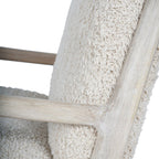 Detail of the whitewashed wooden arm meeting the back upright beside pale teddy upholstery.