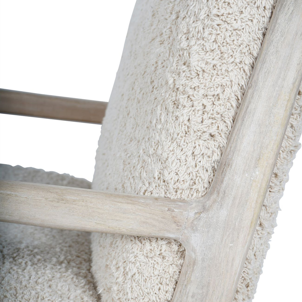 Detail of the whitewashed wooden arm meeting the back upright beside pale teddy upholstery.