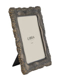 Angled view of a dark metallic photo frame with a heavily textured irregular edge, gold-toned highlights and a black rear support on a white background.