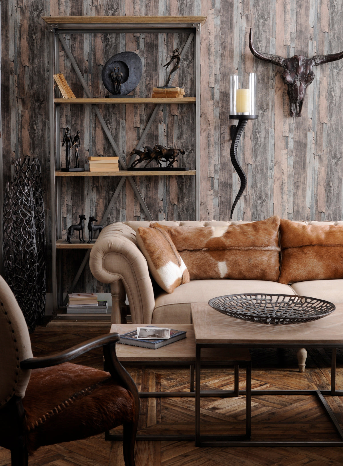 Living room with figurative ornaments and books on wood and metal shelving behind a beige sofa and wooden coffee tables.