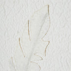 Close-up of a raised pale feather form with fine tan edges against the rippled white background.