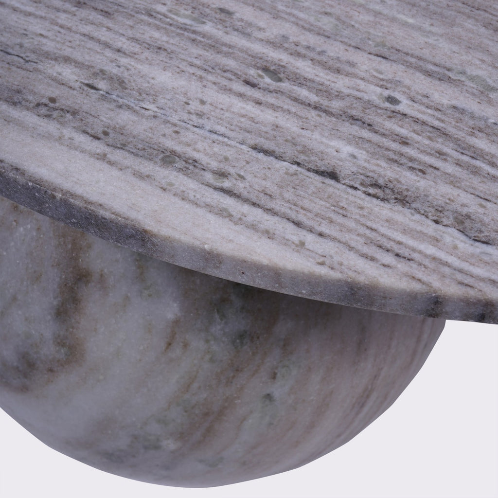 Close-up of the veined marble tabletop and curved edge above one rounded marble foot.