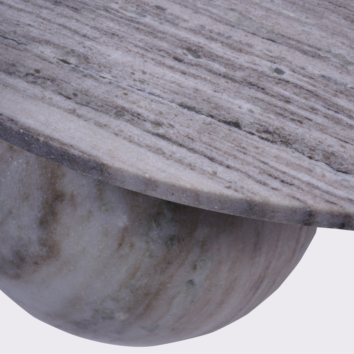 Close-up of the veined marble tabletop and curved edge above one rounded marble foot.