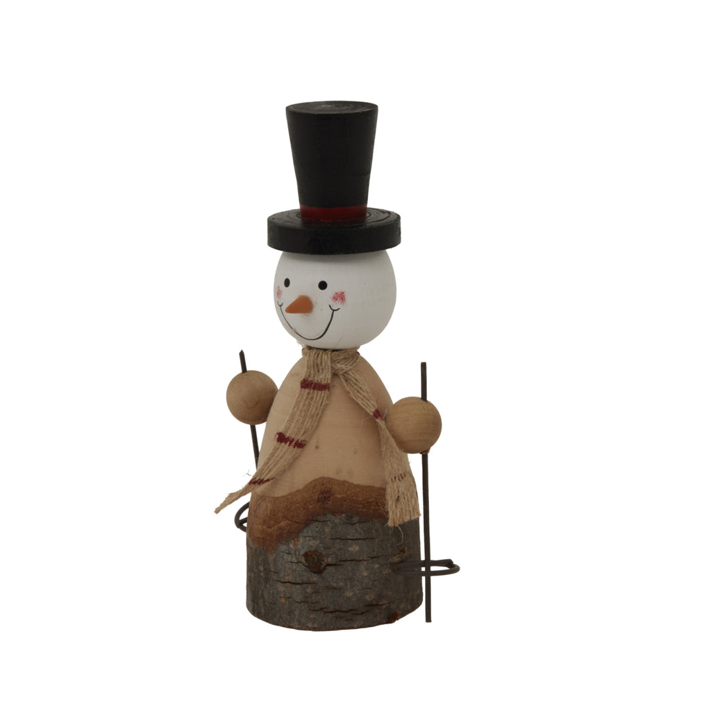 Angled view of the skiing snowman decoration showing its projecting orange nose, draped striped scarf and rough bark-textured base.