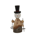 Front view of a smiling snowman decoration with a tall black top hat, red-striped scarf and ski poles beside a bark-covered base.