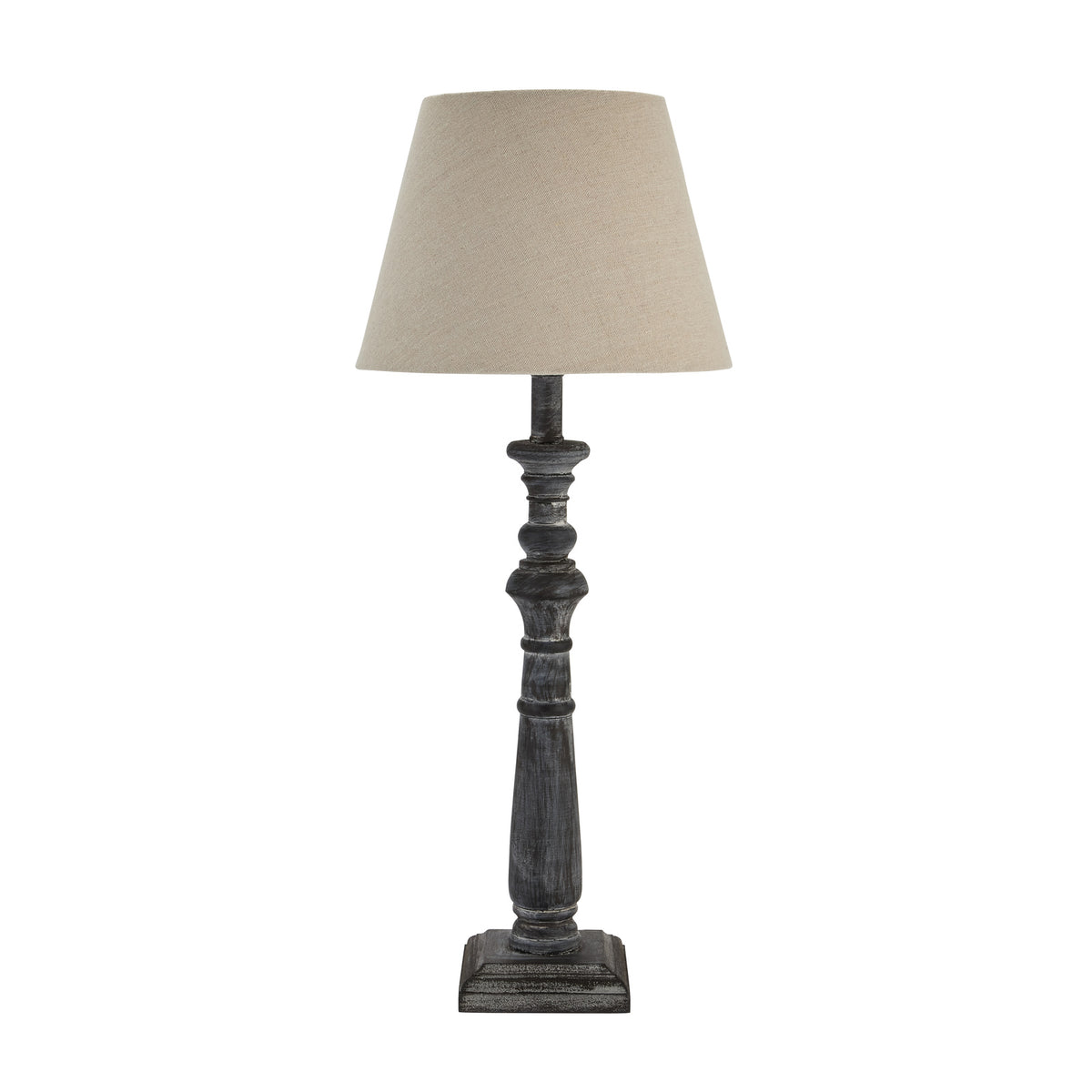 Unlit table lamp with a pale tapered shade, dark grey-washed turned column and stepped square base against white.