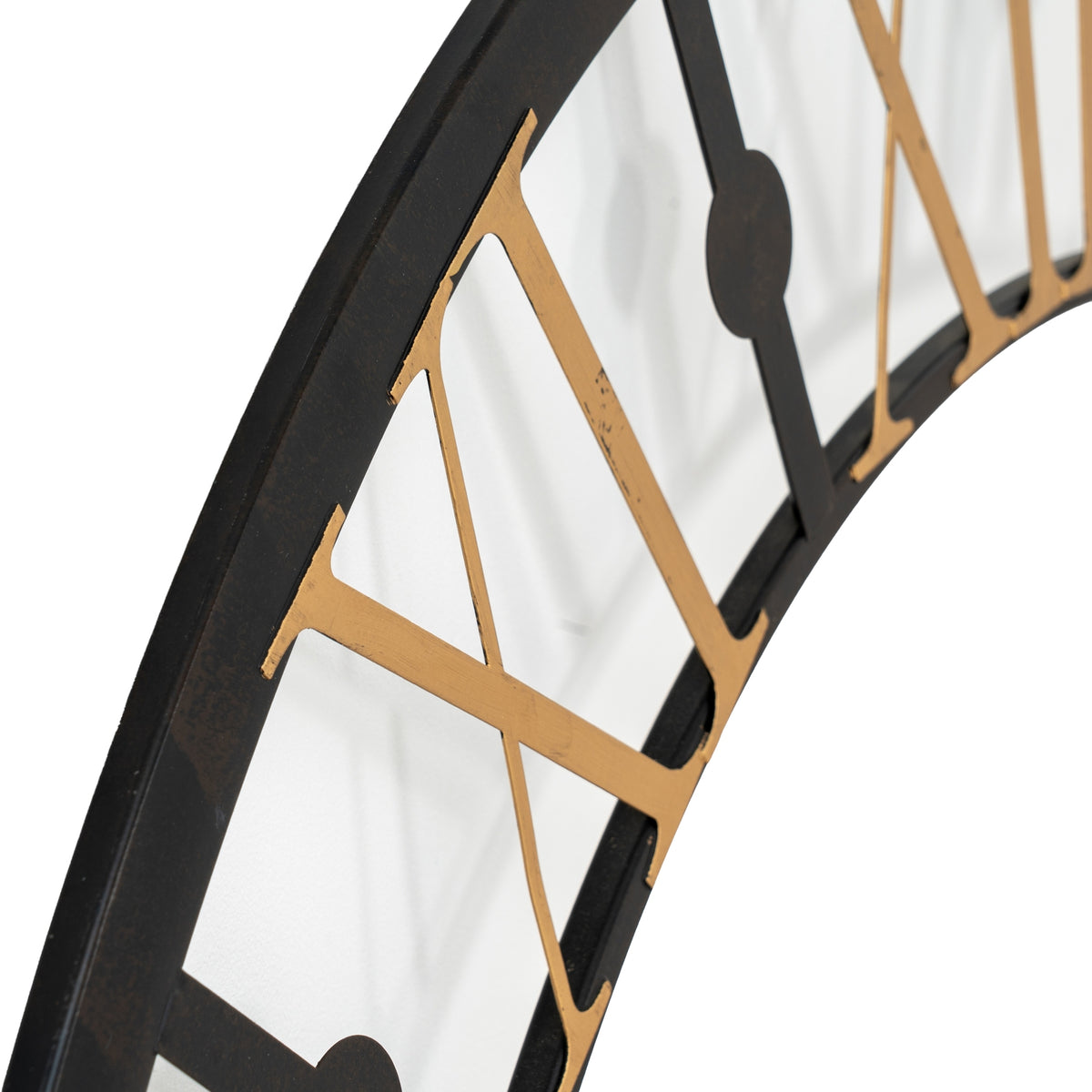 Angled close-up of gold-tone Roman numerals on the black clock frame, showing subtle surface markings and a round hour marker.