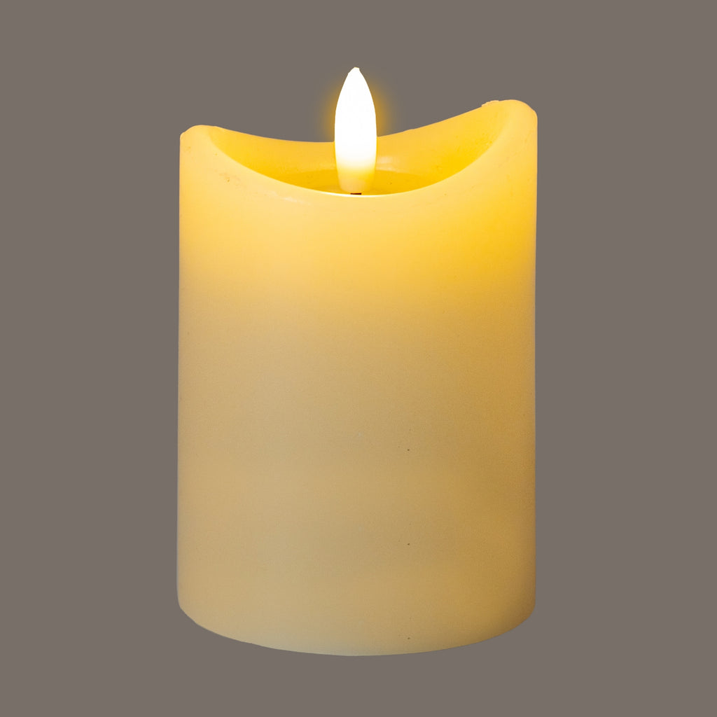 Cream LED candle photographed glowing yellow against a grey background, with a bright flame-shaped centre above the dipping rim.