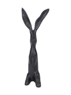 Front view of a black upright hare sculpture with long ears, an elongated body and small forepaws against its chest.