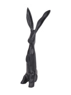 Angled side view of the black hare sculpture showing its projecting muzzle, long ears and rounded hindquarters.