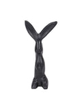 Front view of a black upright hare sculpture with long splayed ears, a slender body and rounded haunches on a white background.