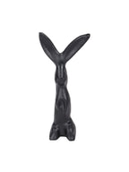 Front view of a black upright hare sculpture with long splayed ears, a slender body and rounded haunches on a white background.