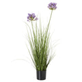 Full view of an artificial arrangement with purple flower clusters at different heights above dense green foliage in a black pot.