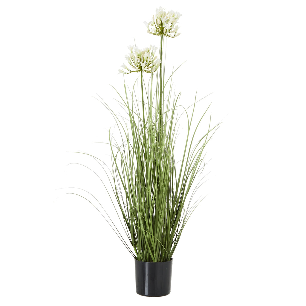 Full view of a tall artificial arrangement with white flower clusters above long green leaves in a black pot.