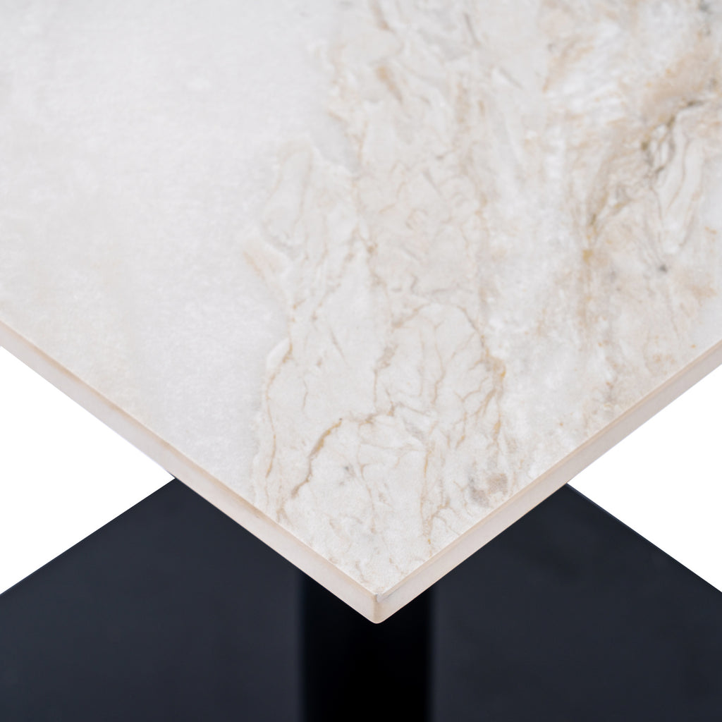 Close-up of the pale tabletop corner showing fine grey and beige veining, a slim edge and part of the dark base below.