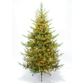 Full green artificial tree with tiered needle-like branches and glowing warm-yellow light points, on a dark splayed stand against a pale background, with a thin cable extending to the right.
