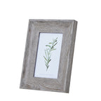 Angled front view of a portrait photo frame with a broad pale grey-brown woodgrain-look border around a green leafy illustration.