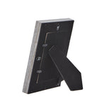 Rear view of the photo frame with its black folding easel extended, retaining tabs and hanging loops visible.