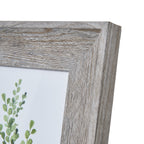 Close-up of the frame's upper right mitred corner, showing pale highlights across the grain pattern and part of a green botanical illustration.