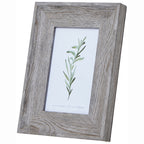 Angled front view of a portrait photo frame with a broad pale grey-brown grain-patterned border and a green leafy illustration inside.