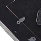 Close-up of a rotating retaining tab across the edge of the black rear panel, with the easel hinge visible to the right.