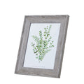 Angled front view of a portrait photo frame with a broad pale grey-brown woodgrain-look border and green botanical insert.