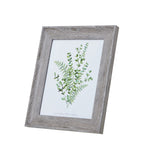 Angled front view of a portrait photo frame with a broad pale grey-brown woodgrain-look border and green botanical insert.