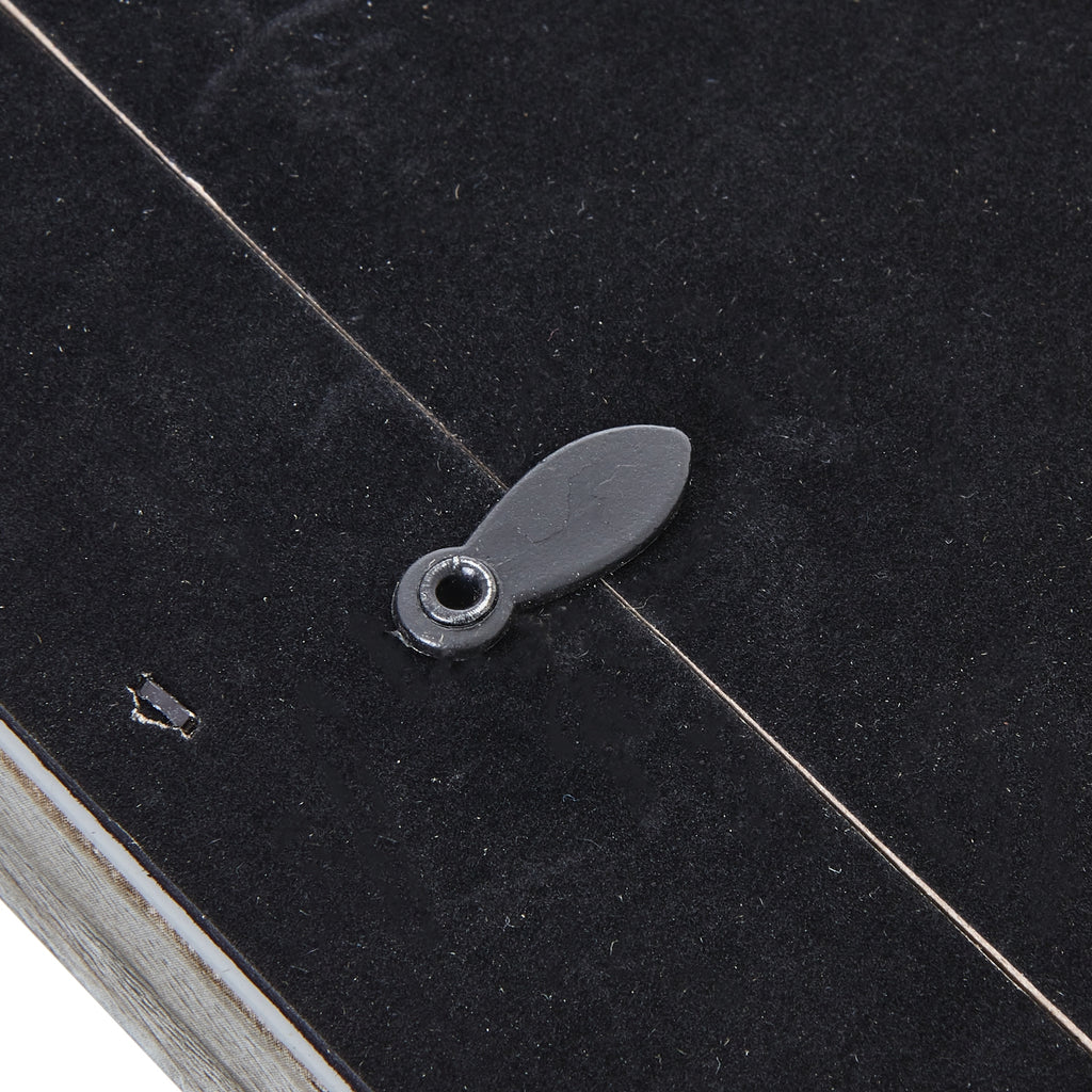 Close-up of an oval rotating retaining tab crossing the edge of the photo frame's black rear panel.