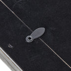 Close-up of an oval rotating retaining tab crossing the edge of the photo frame's black rear panel.