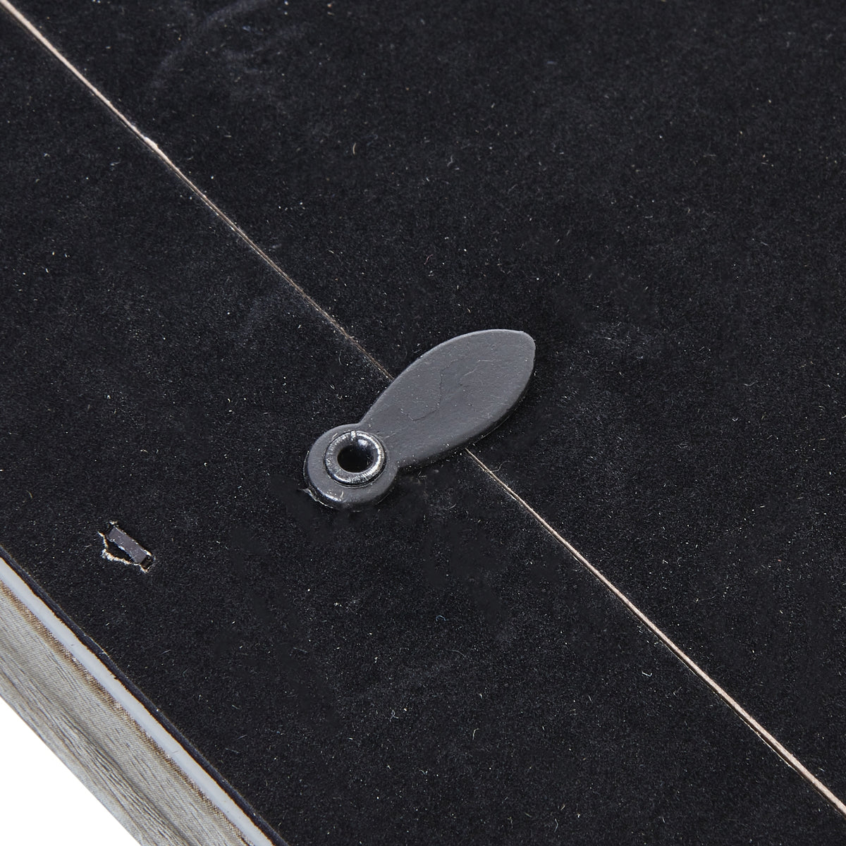 Close-up of an oval rotating retaining tab crossing the edge of the photo frame's black rear panel.