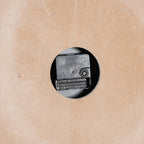 Rear clock detail showing a black movement, adjustment wheel and empty battery compartment through a round cutout in the brown backing.