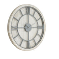 Angled view of a round whitewashed wall clock with light-grey Roman numerals, circular framework and three grey hands.