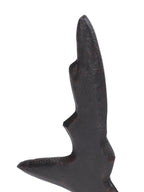 Close-up of the sculpture's pointed upper section showing a dark textured finish and warm-toned raised edges.