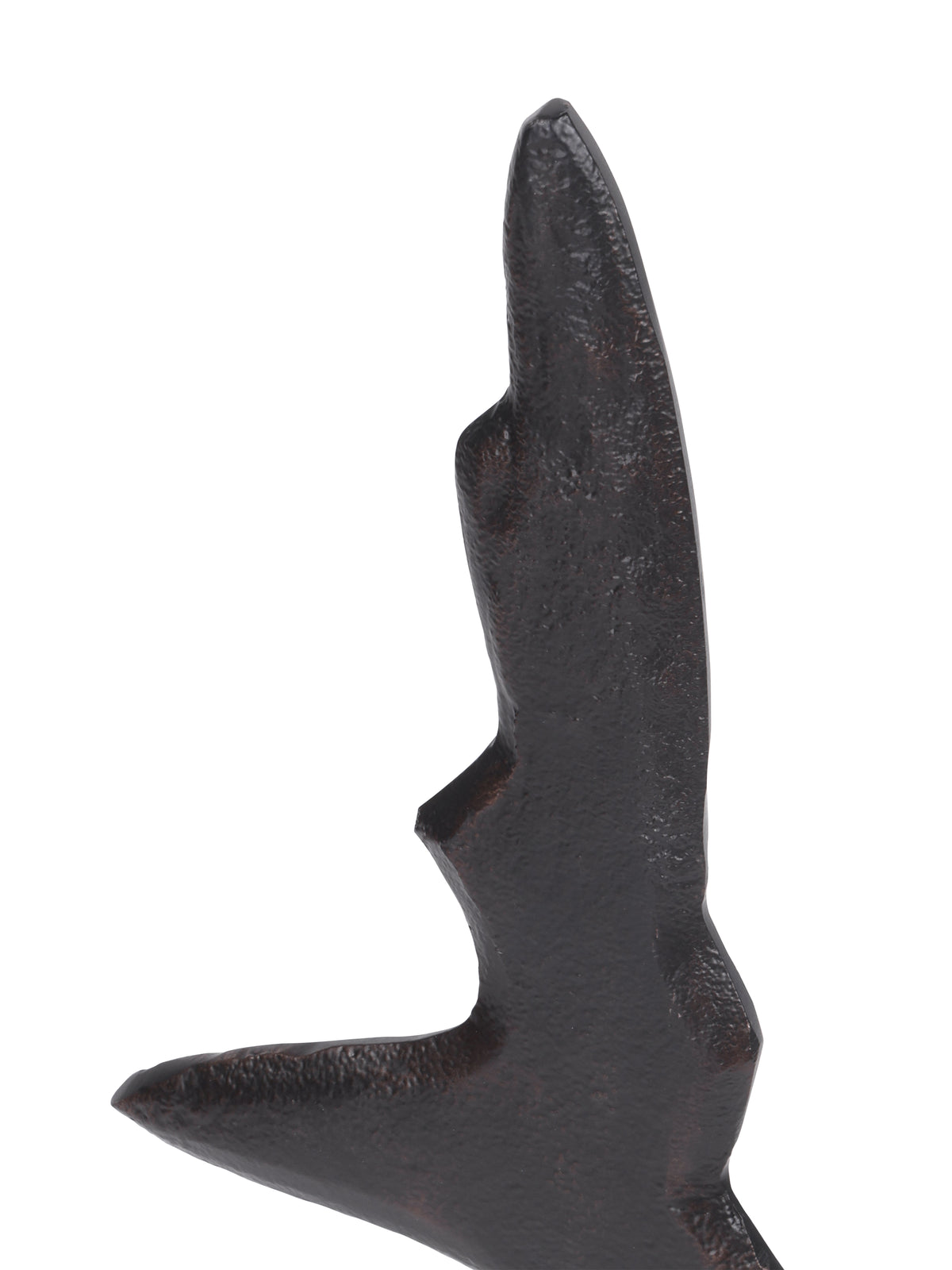 Close-up of the sculpture's pointed upper section showing a dark textured finish and warm-toned raised edges.