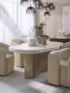Waveline dining table with cream upholstered chairs, stacked crockery and sculptural vessels beneath a glass globe pendant.