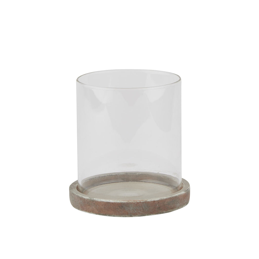 Candle lantern with a clear open cylindrical sleeve seated in a shallow mottled brown and grey base, shown against white.
